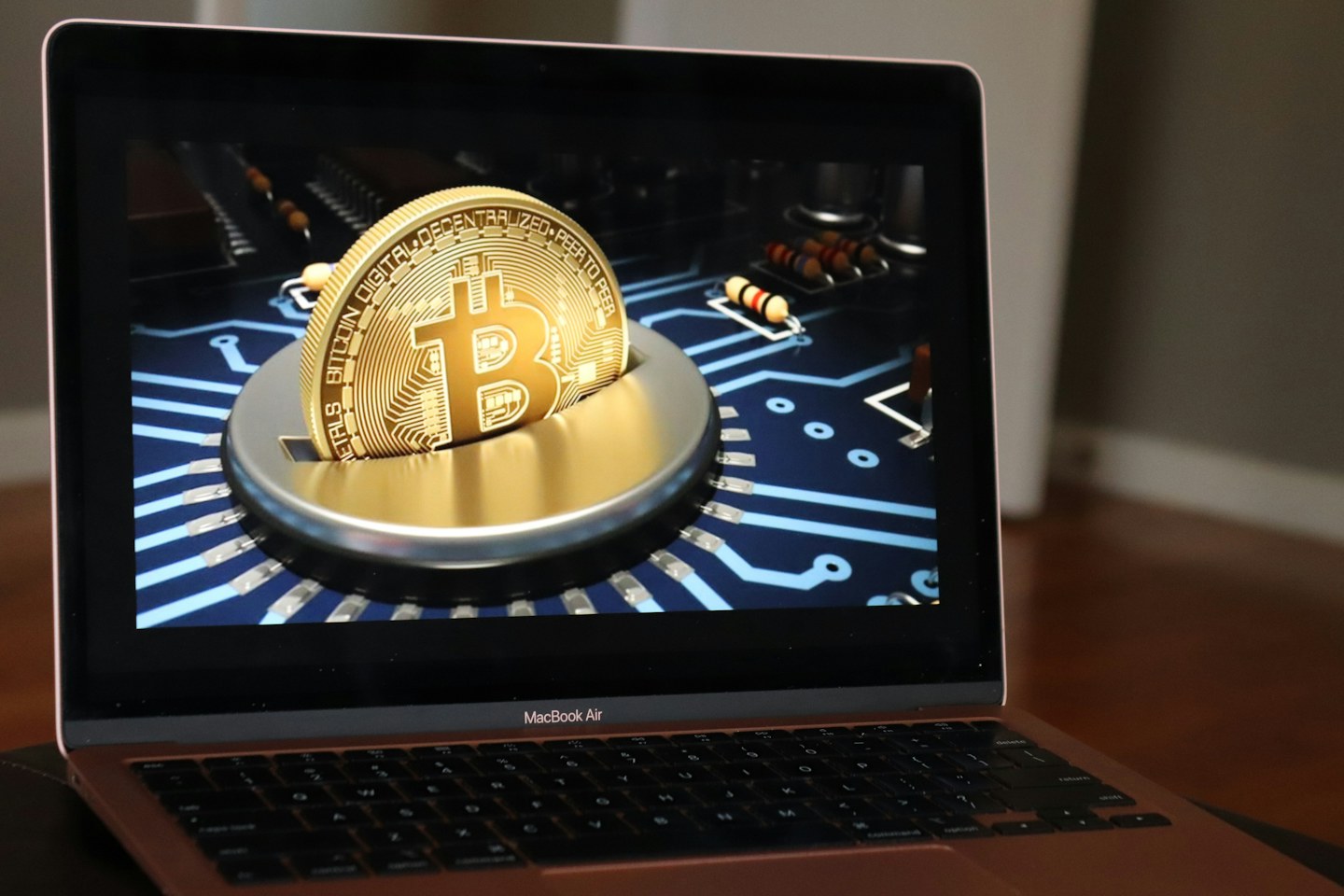 A laptop displays a Bitcoin design on a digital circuit background.
